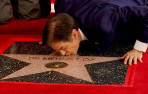 Mehmet Oz, the former host of ‘The Dr. Oz Show,’ kisses his new star on the Hollywood Walk of Fame during a ceremony on Friday in Los Angeles. 
                                 Chris Pizzello | AP photo